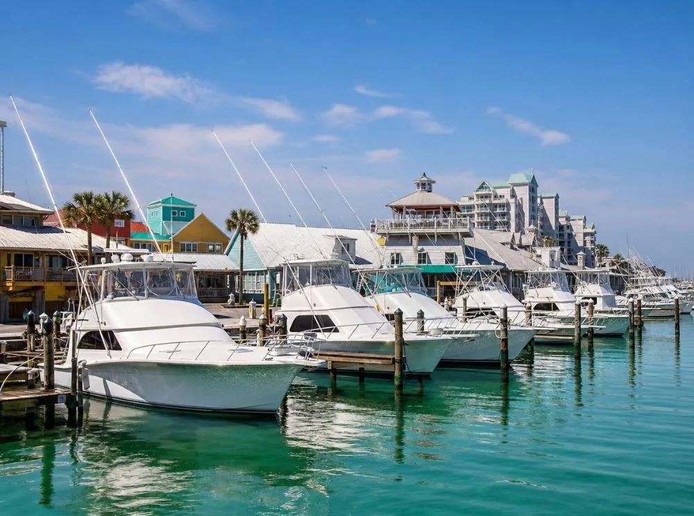 Charter fishing boats with tall outriggers tied up at the docks of a sunny harbor